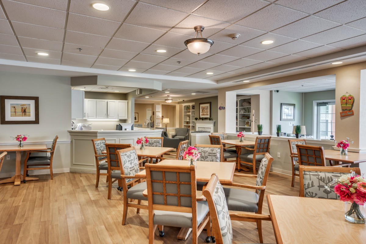 A spacious dining area with neatly arranged tables and chairs, accented with warm lighting and decor.