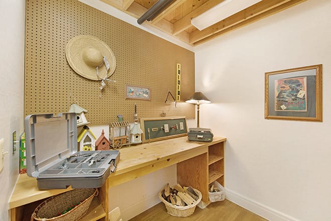 A cozy workshop area with a wooden desk, pegboard for tools, and decorative items.
