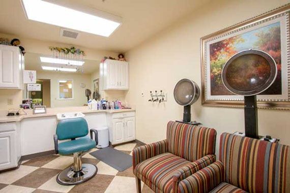 A cozy hair salon interior with a salon chair, hair dryer, and waiting area seating.