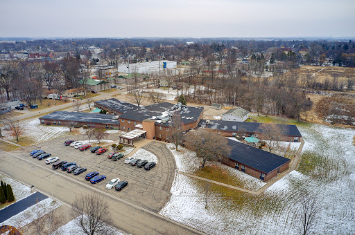 An aerial view of a school campus surrounded by winter scenery and a parking lot.