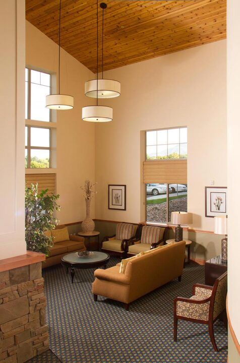 A modern lobby area with comfortable seating and large windows, featuring contemporary lighting and decor.