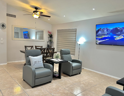 A cozy and modern living room featuring comfortable gray chairs, a dining area, and a television.