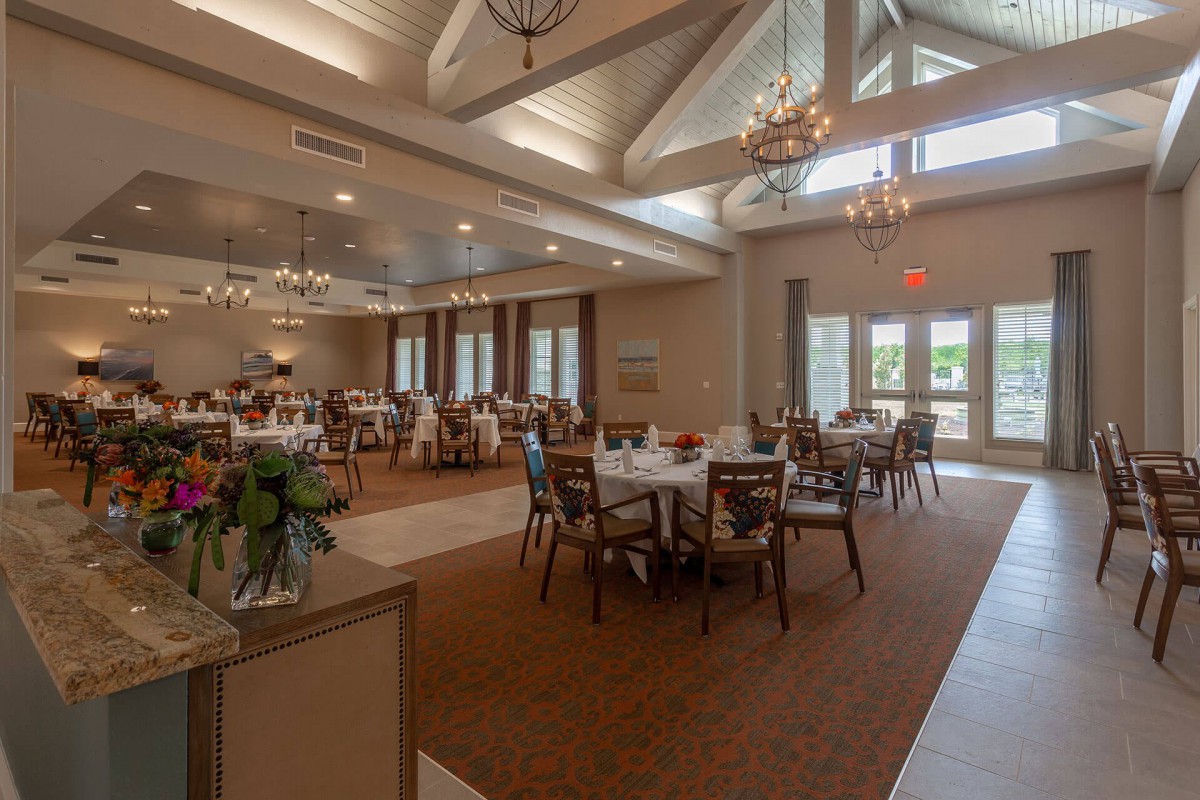 An elegant dining room with chandeliers, natural lighting, and well-arranged tables.