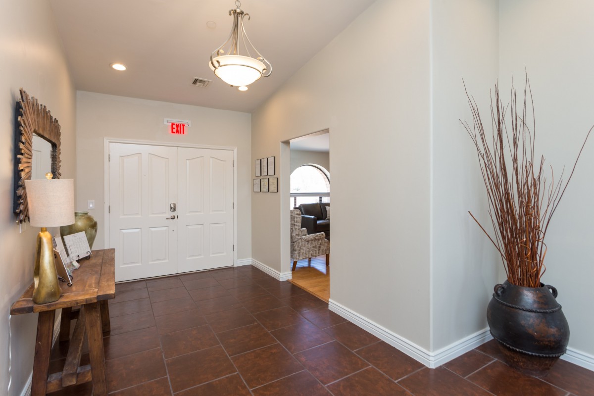 A modern entryway with a light fixture and tiled floor, leading to a living area.