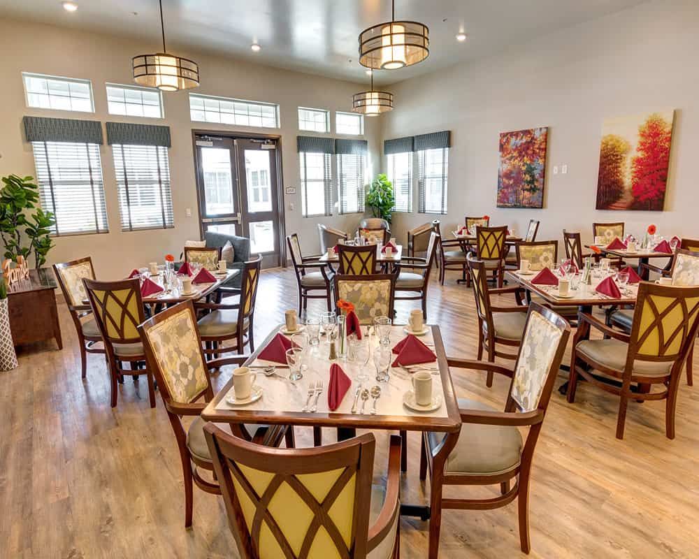 An elegant dining room with neatly arranged tables and chairs, set for guests.