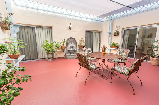 A serene patio setting with decorative plants, a classic fountain, and comfortable seating for relaxation.