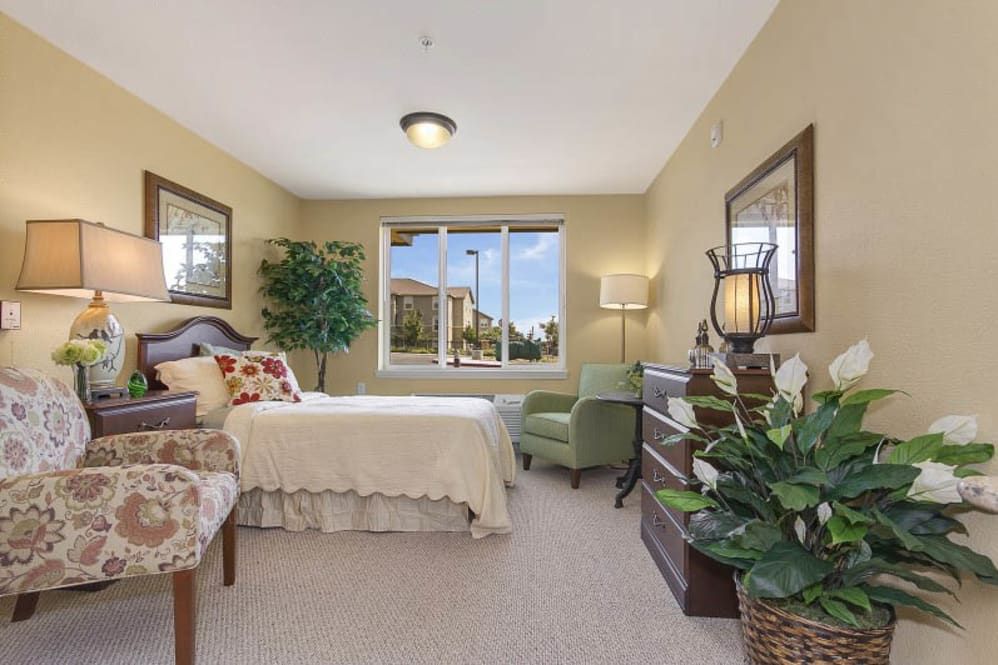A cozy bedroom with elegant decor, featuring a large window allowing natural light to illuminate the room.