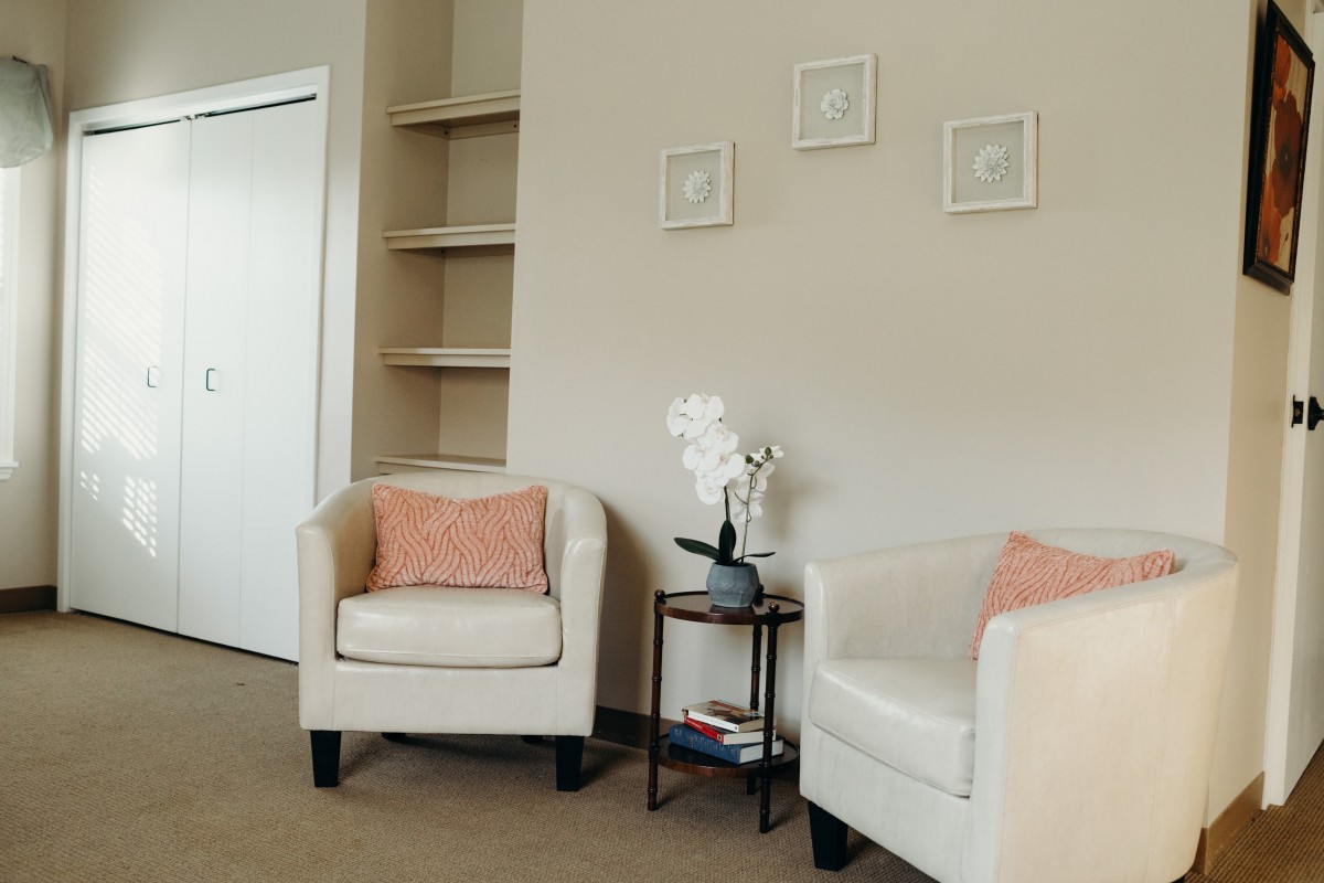 A modern living room with beige chairs and minimalist decor.