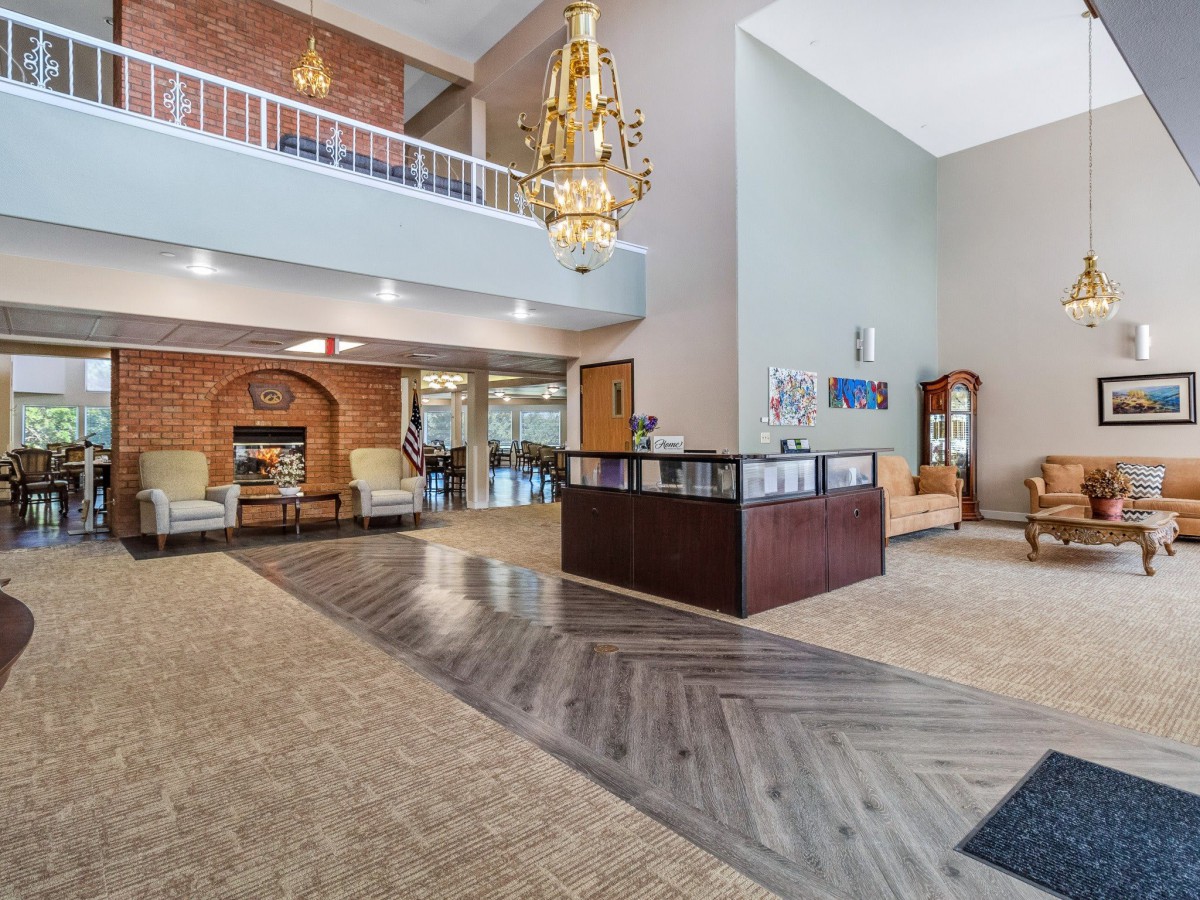 A spacious lobby with a reception desk, chandelier, and comfortable seating areas.