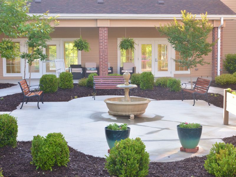 A serene courtyard with a central fountain, surrounded by lush greenery and seating areas.
