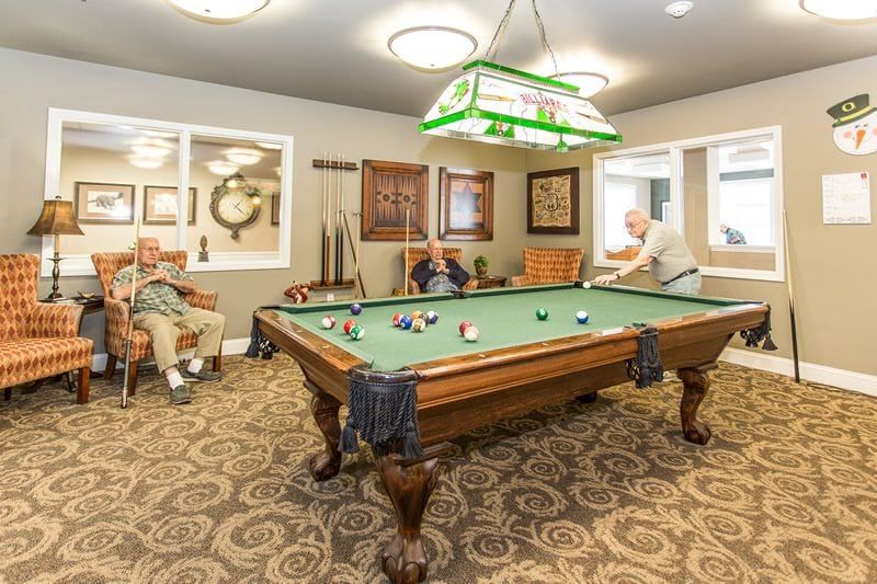 Seniors playing billiards in a cozy recreation room.