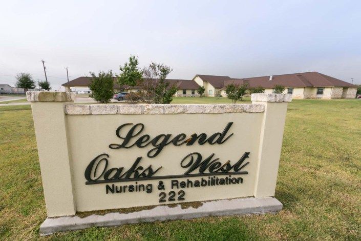 Sign for Legend Oaks West Nursing & Rehabilitation facility with buildings in the background.
