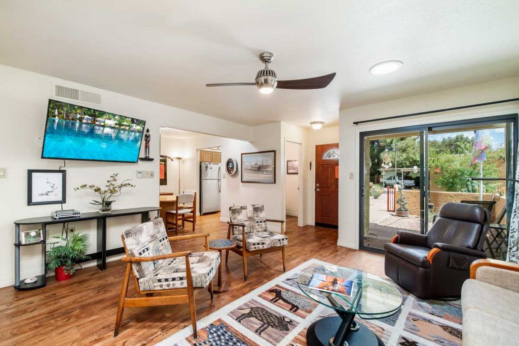 A cozy living room with a modern design featuring a ceiling fan, wooden flooring, and comfortable seating.