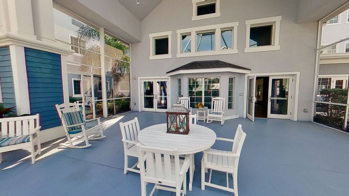 A spacious patio area with a dining set and a decorative lantern, surrounded by large windows.