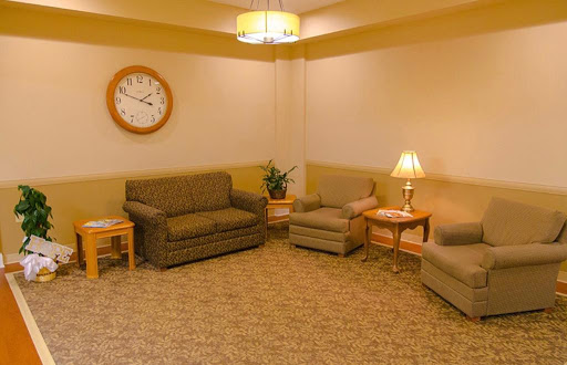 A cozy living room featuring comfortable sofas, a wall clock, a lamp, and a decorative plant.