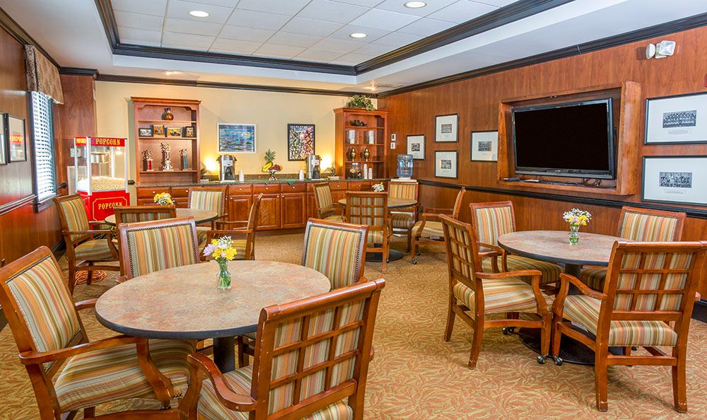 An elegant lounge with tables and chairs, featuring wood paneling and decorative elements.