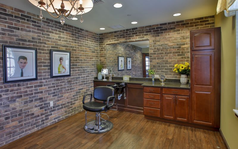 A stylish hair salon with brick walls, a mirror, and a haircut chair.