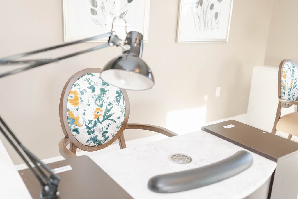 A bright and modern workspace with a floral patterned chair and a desk lamp.