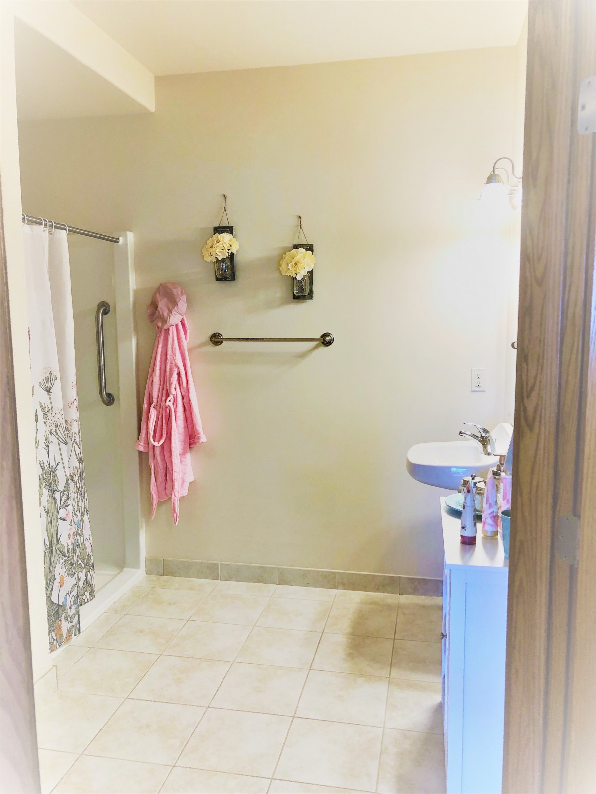 A clean and tidy bathroom with a shower area, sink, and neatly hung towels.