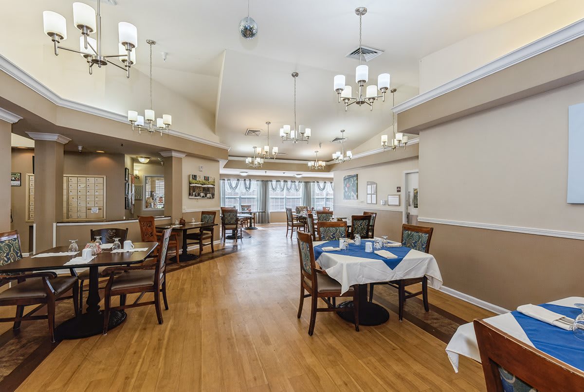 A spacious dining area with neatly arranged tables, chairs, and elegant chandeliers.
