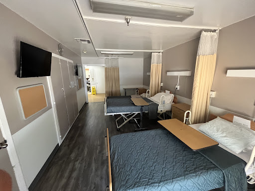 A view of a hospital patient room featuring two beds and modern amenities.
