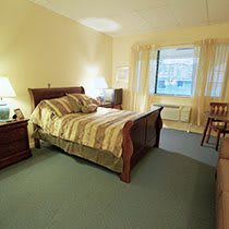 A cozy bedroom interior with a neatly made bed, bedside lamps, and a large window.