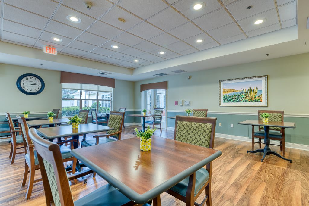 A well-lit dining area with wooden floors and neatly arranged tables and chairs.