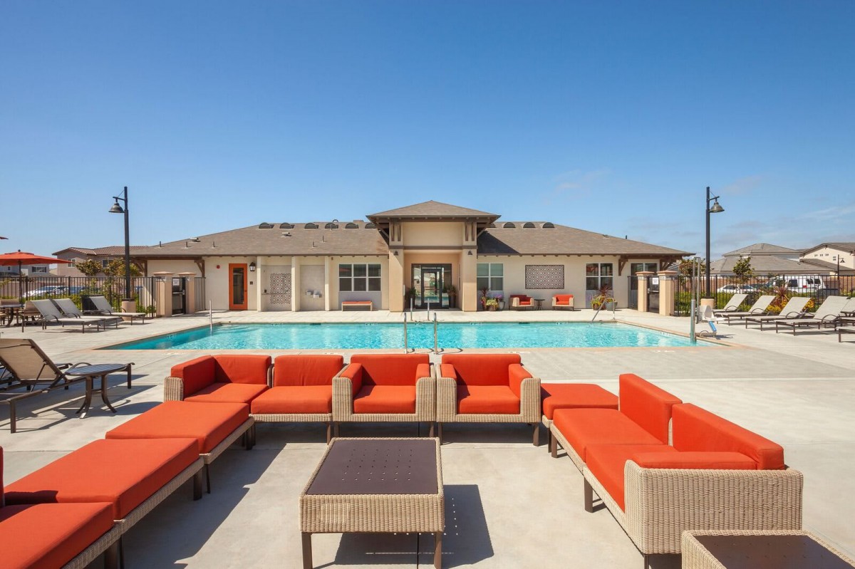 Luxury outdoor seating area by a swimming pool on a sunny day.