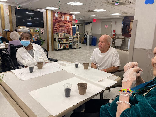 A group of senior citizens engaged in a discussion in a community healthcare setting.