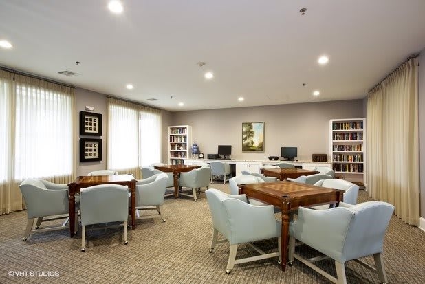 A quiet library with tables, comfortable chairs, and bookshelves filled with books.