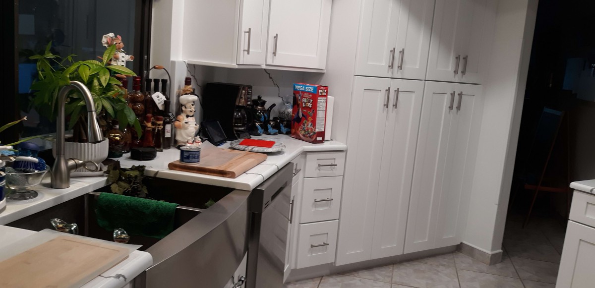 A modern kitchen with white cabinets and various items on the countertop.
