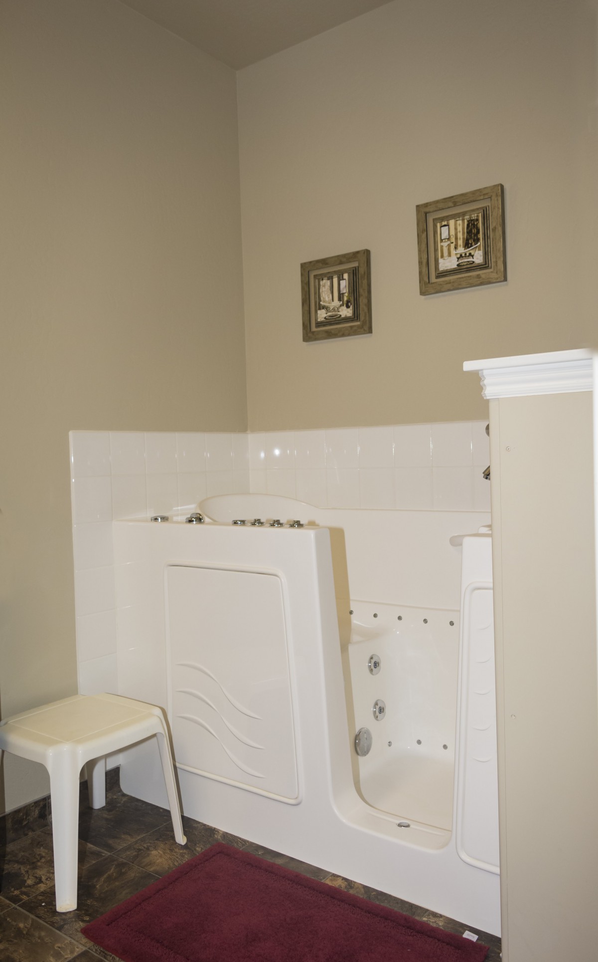 A bathroom featuring a bathtub with beige walls and framed artwork.