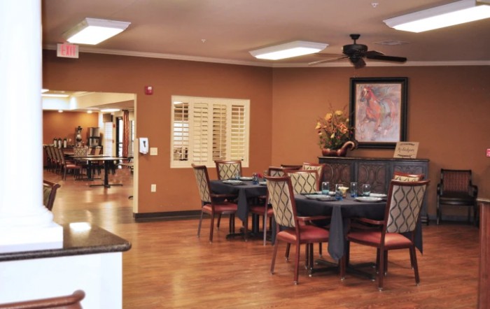 A cozy dining area with neatly arranged tables and chairs, featuring warm lighting and tasteful decor.