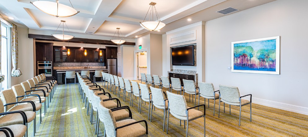 A modern conference room with rows of chairs facing a large screen.