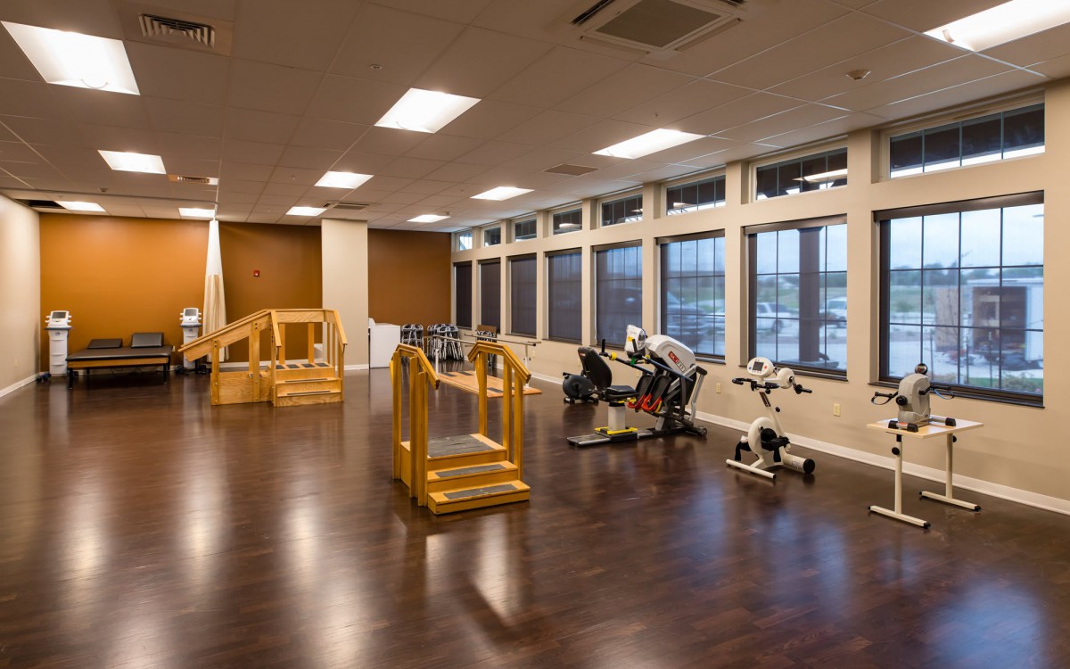 A spacious rehabilitation room equipped with exercise machines and therapy tools.