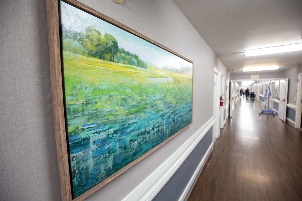 A hallway featuring a large landscape painting on the wall.