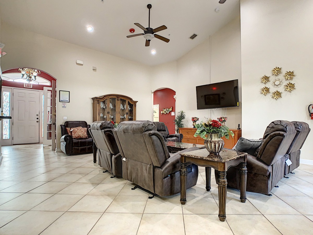 A spacious living room with comfortable recliners, a wall-mounted TV, and tile flooring.