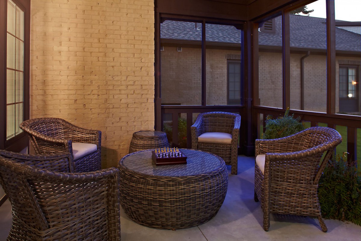 An outdoor patio with wicker furniture set including chairs and a round table.