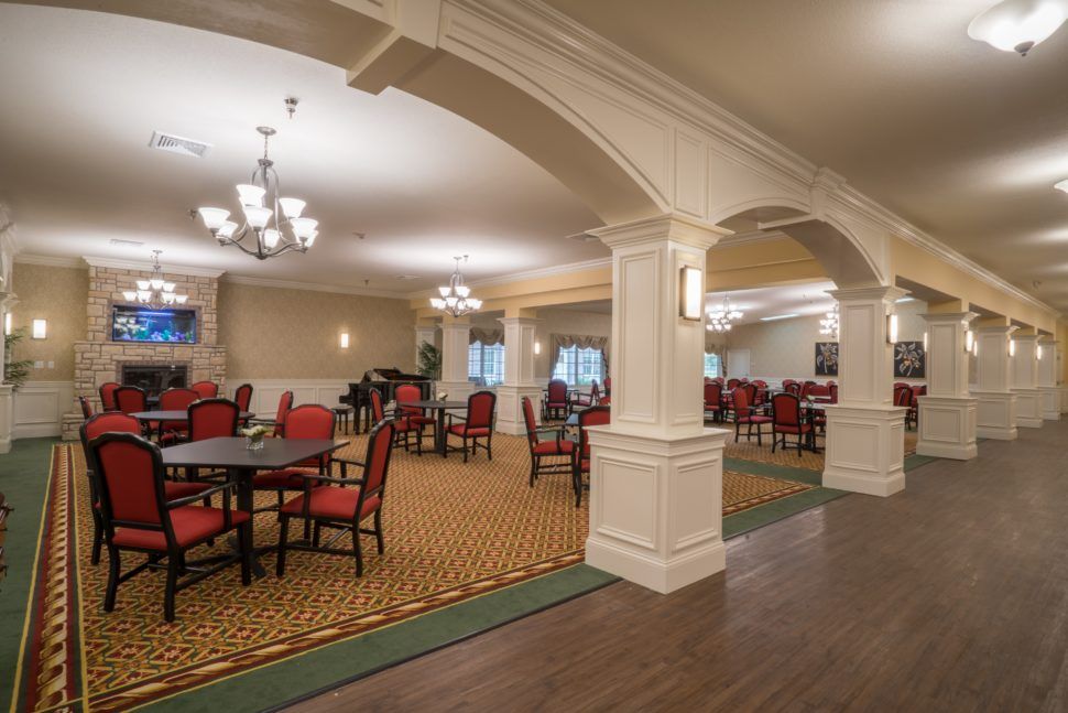 A spacious and elegantly decorated dining area with red chairs and large archways.