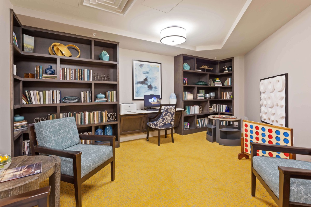 A cozy library with bookshelves, chairs, and decorative elements.