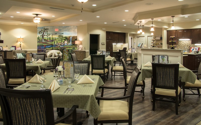 A cozy restaurant dining area with elegantly set tables and comfortable chairs, featuring warm lighting and tasteful decor.