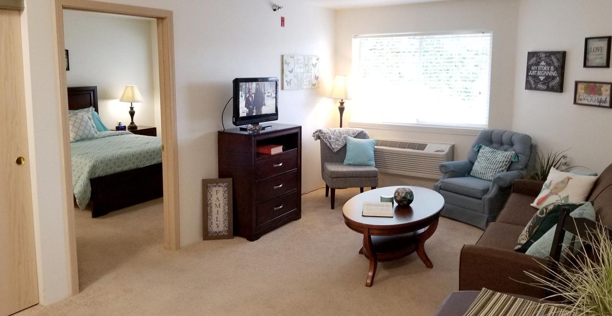 A cozy living room with comfortable seating, a television, and a window letting in natural light.