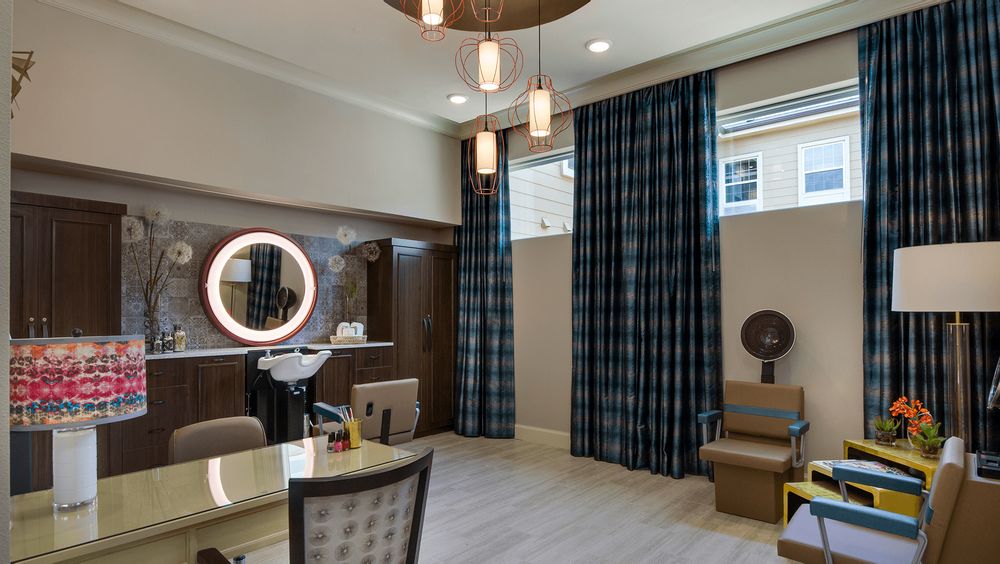 A modern salon interior with stylish lighting, a ring mirror, and comfortable seating.