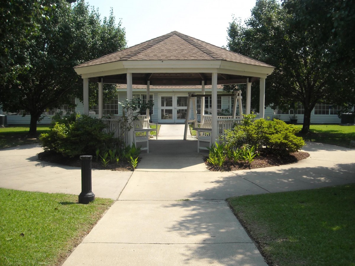 A peaceful gazebo surrounded by a landscaped garden and trees.