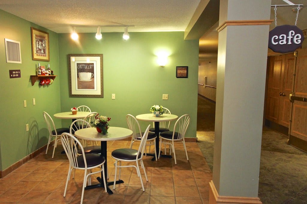 Cozy cafe interior with green walls and seating area.