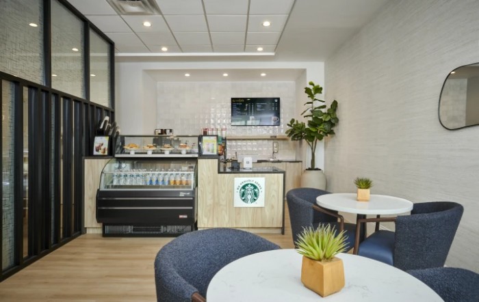 A modern Starbucks coffee shop interior featuring a seating area with plants and a stylish counter.