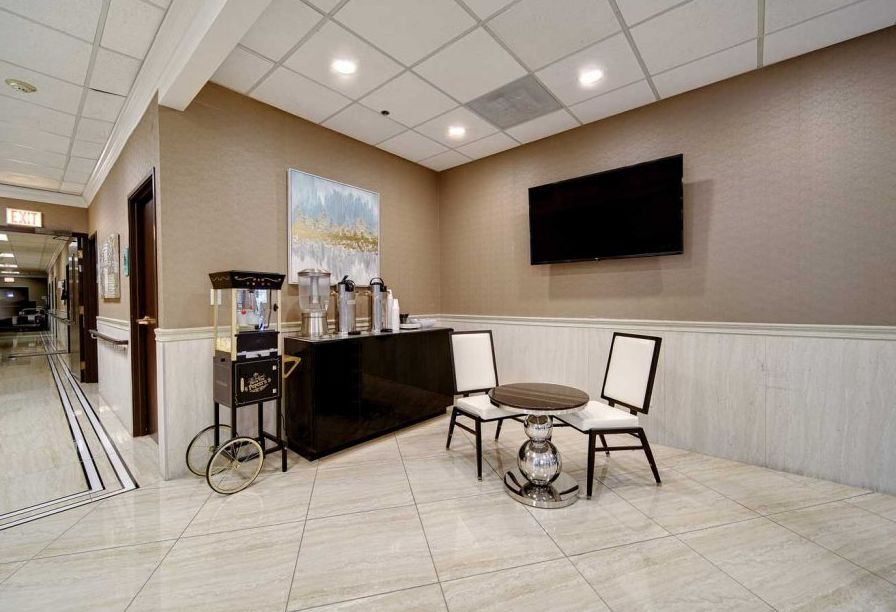 A modern waiting area with seating and a beverage station, featuring a coffee machine and water dispenser.