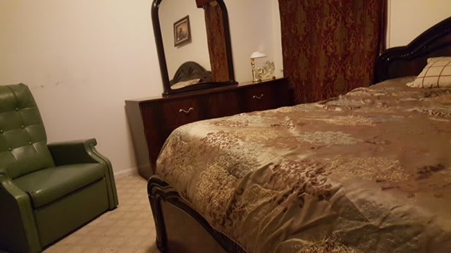A cozy bedroom featuring a bed with patterned bedding and a dresser with a mirror.