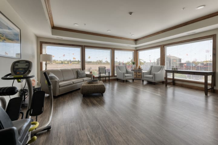 A modern living room with large windows, sleek furniture, and a hardwood floor.