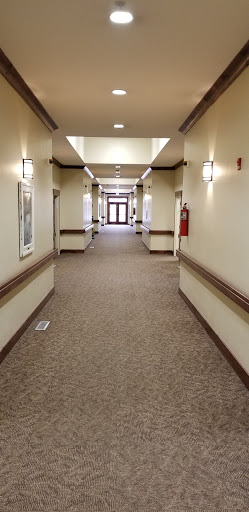 A spacious and well-lit hallway with carpeted flooring, leading to doors at the end.